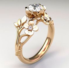 a gold ring with flowers on it and a diamond in the center, sitting on a white surface