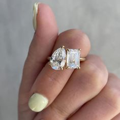 a woman's hand holding an engagement ring with three stones