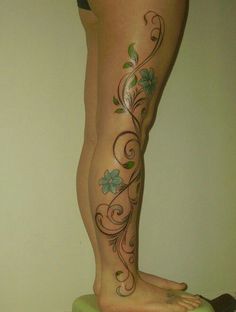 a woman's legs with flowers and vines tattooed on the side of her leg