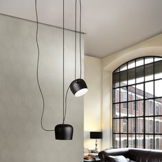 three black lamps hanging from the ceiling in a living room next to a couch and table