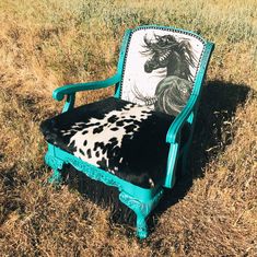 a cow print chair sitting on top of a dry grass field