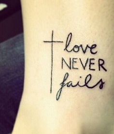 a tattoo with the words love never falls on it and a cross in black ink