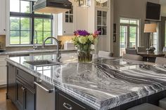 a large kitchen with marble counter tops and an island in front of the dining room