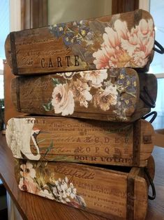 three wooden boxes are stacked on top of each other, with floral designs and words painted on them