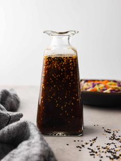 a glass bottle filled with liquid sitting on top of a table next to a bowl