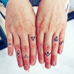 two fingers with small tattoos on them, one has a diamond and the other has an arrow