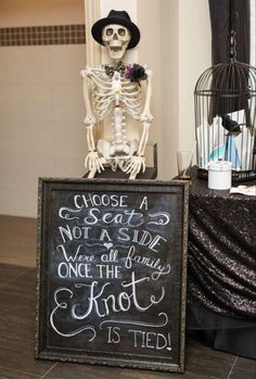 a chalkboard sign with a skeleton on it and a birdcage behind it