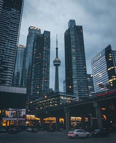 some very tall buildings and cars in the street at night with lights shining on them