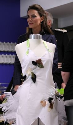 a woman standing next to a mannequin wearing a dress with flowers on it