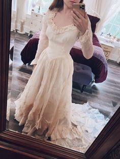 a woman taking a selfie in a mirror wearing a wedding dress and holding a cell phone