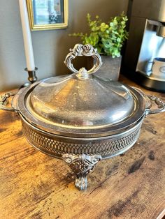 a silver covered dish sitting on top of a wooden table