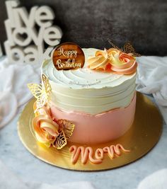 a birthday cake on a plate with the name mom written in frosting and butterflies