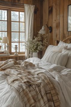 an unmade bed with white sheets and pillows in a rustic cabin style bedroom area