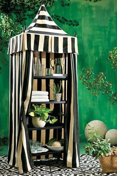 a black and white striped gazebo sitting on top of a table next to potted plants