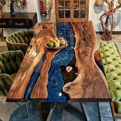 a dining table made out of wood with green chairs around it and a bowl of fruit on top