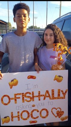 two people holding up a sign that says i'm fish ally asking you to hoco