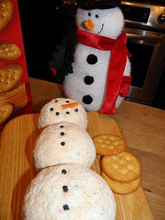 snowmen made out of crackers and cookies on a wooden cutting board next to them