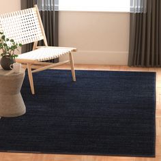 a chair sitting on top of a wooden floor next to a blue rug in front of a window