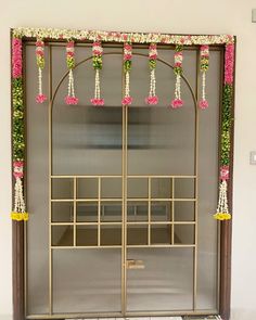 an entrance to a building decorated with pink flowers and greenery on the door frame