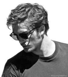 a man with sunglasses on his face looking down at something in the distance while wearing a t - shirt