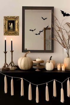 a mantle with candles, pumpkins and bats on it in front of a mirror