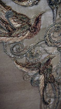 closeup of an embroidered fabric with gold and silver beads on the back of it