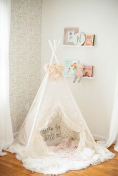 a teepee tent sitting on top of a wooden floor next to a white wall