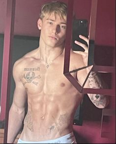 a shirtless man taking a selfie in the mirror