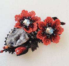 two beaded flowers and a rock on a white surface