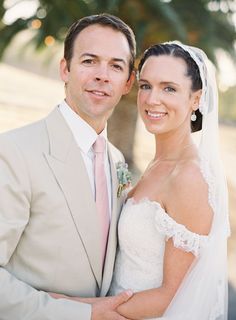 a bride and groom standing next to each other in front of a palm tree on their wedding day