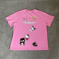 a pink t - shirt with cartoon characters printed on the front and back, sitting on a gray surface