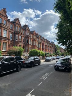 several cars parked on the side of a road in front of some tall brick buildings