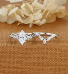 two wedding rings sitting next to each other on a table with flowers in the background