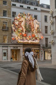 a woman is walking down the street in front of a building with an elaborately decorated facade