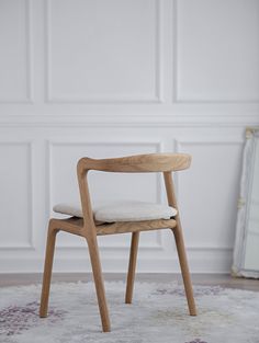 a wooden chair sitting on top of a rug in front of a white wall and floor