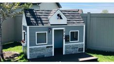 a small dog house made out of wood and stone with a roof that has windows on it