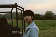 a young man standing next to a truck in a field