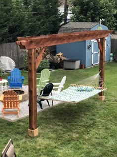 a backyard with lawn chairs and a hammock in the middle, next to a fire pit