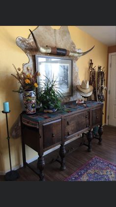 a wooden table topped with lots of plants and vases next to a wall mounted mirror