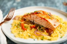 a white plate topped with salmon and rice