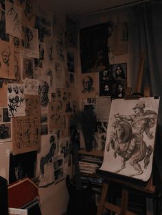 an artist's studio with various drawings and paintings on the wall