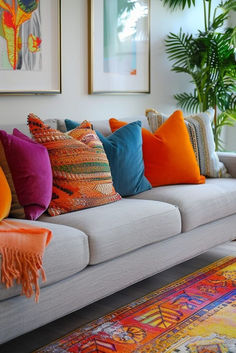 a living room filled with lots of pillows on top of a white couch next to a potted plant