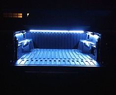 the back end of a truck with its bed lit up in the dark at night