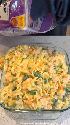 a casserole dish filled with noodles and vegetables next to a bottle of milk