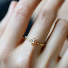 a woman's hand wearing a gold ring with three small flowers on the band