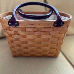 a wicker basket with leather handles sitting on a couch