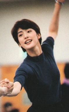 a woman holding a tennis racquet on top of a hard wood floor in front of an audience