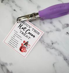 a pair of purple scissors sitting on top of a white marble counter next to a card