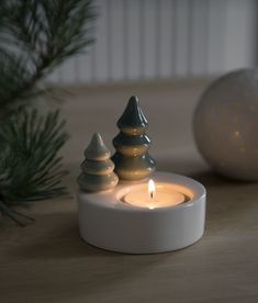 a lit candle sitting on top of a table next to a christmas tree ornament