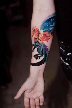 a person's arm with a tattoo on it and an image of trees in the background